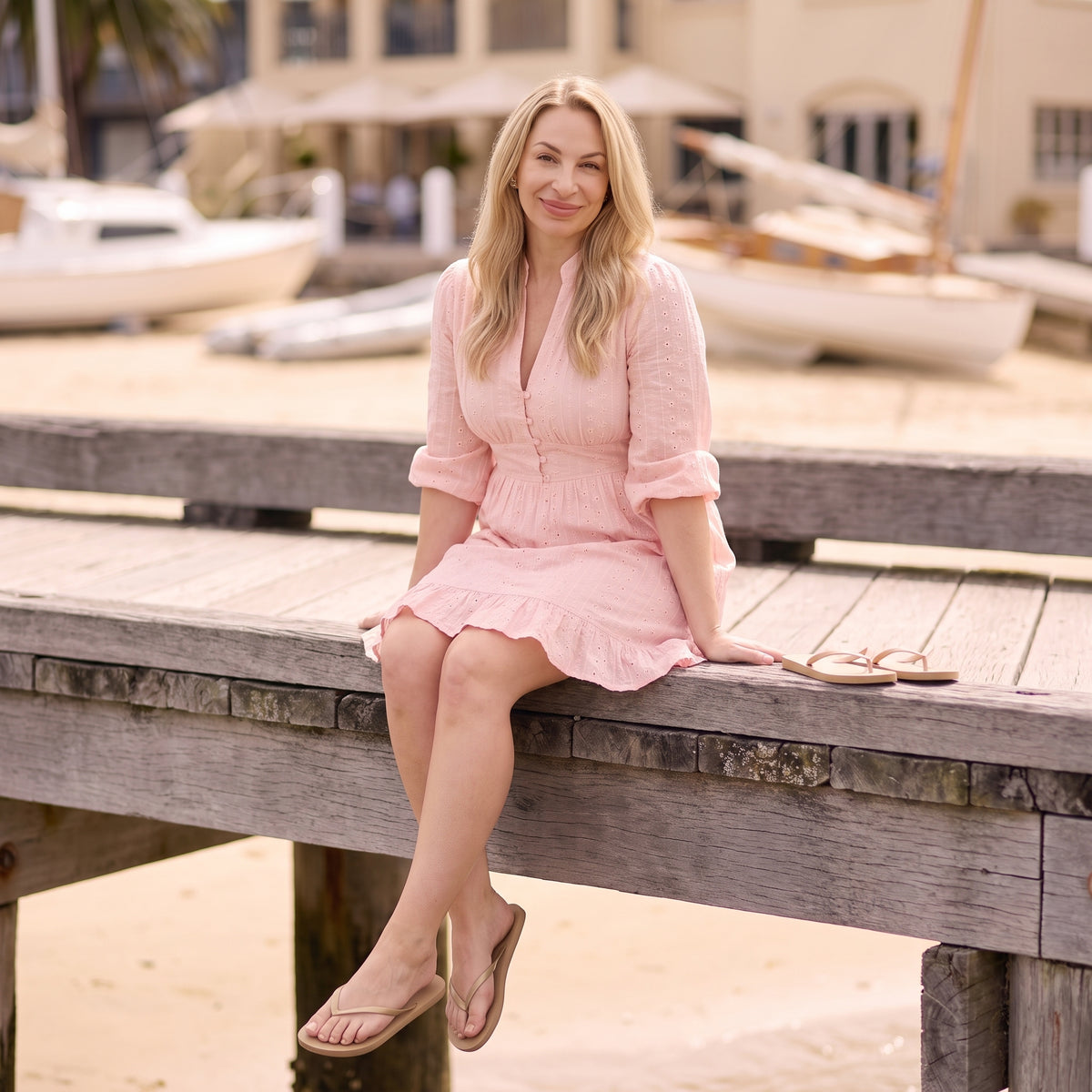 Rosie pink broderie mini dress seated by Riley Belle